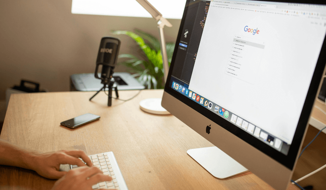 Ein Nutzer sitzt am Schreibtisch und verwendet Google auf einem iMac. Die Szene zeigt die Online-Recherche im Kontext von Google Agentur und Sichtbarkeit.